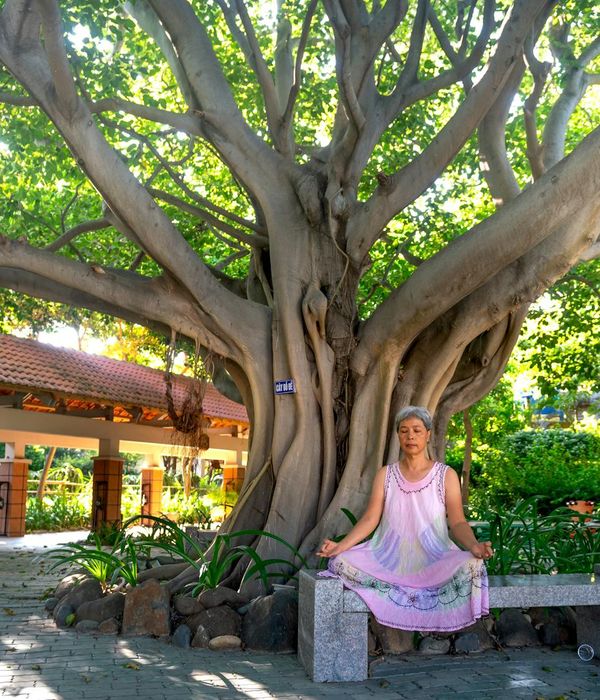 Smiling woman stretching gently on a yoga mat outdoors.